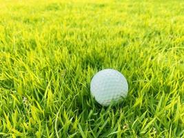 pelota de golf cerca de la hierba verde en el hermoso paisaje borroso del campo de golf con amanecer, atardecer en segundo plano. concepto de deporte internacional que se basa en habilidades de precisión para la relajación de la salud. foto