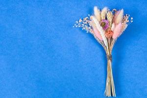 bouquet of dried flower and spikelets lies on blue photo