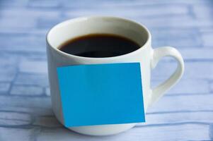 Blank blue notepad stick on coffee cup with customizable space for text or ideas. Copy space concept. photo