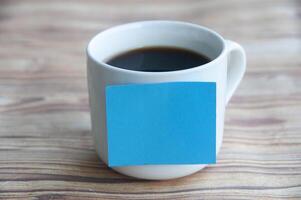 Blank blue notepad stick on coffee cup with customizable space for text or ideas. Copy space concept photo
