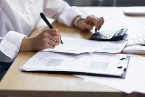 Close-up photo. Hands of a woman.Write documents with a pen,calculate on a calculator in the office photo