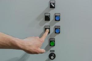 Man engineer worker turns on the buttons on the control panel photo close up of a male hand