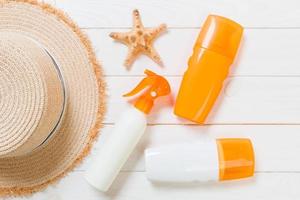 Sunscreen bottles with starfish and sunhat on white wooden table with copy space. Travel healthcare accessories top view photo