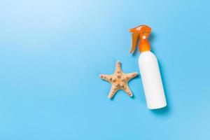 sunscreen cream with starfish and seashells in bottles on blue background, top view photo