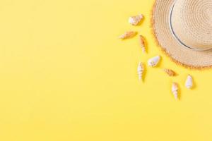 Beach hat with seashells on brown yellow table. summer background concept with copy space top view photo