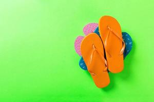 A lot of colored flip flops on green background. Top view with copy space photo