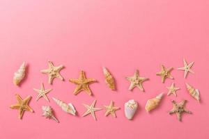 A lot of seashells and starfishon pink background with copy space photo