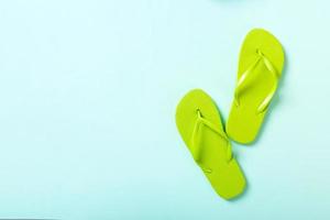 green flip flops on blue background. Top view with copy space photo