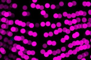 Unfocused abstract purple bokeh on black background. defocused and blurred many round light photo