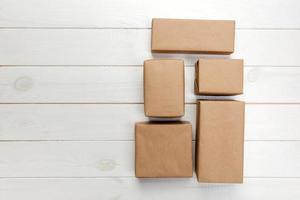 caja de cartón sobre fondo de madera blanca, vista superior del paquete de correo marrón