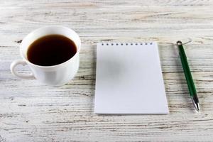 Cup of coffee with notebook on wooden desk, Top view, copy space photo