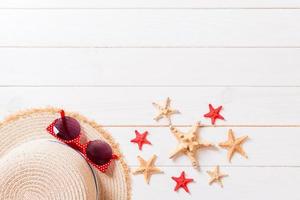 Beach hat with seashells on brown wooden table. summer background concept with copy space top view photo