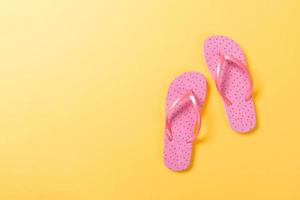 Pink flip flops on yelow Background. Top view with copy space