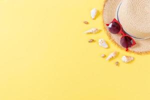 Summer holiday background with straw hat and seashells on yellow background top view with copy space photo