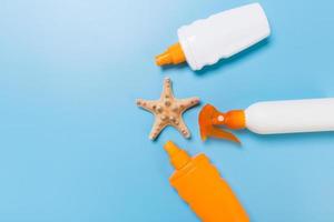 Sunscreen bottles with seashells on blue table top view photo