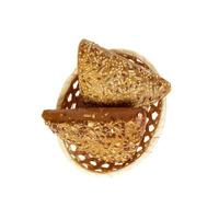 Rye triangle bun sprinkled with sunflower and flax seeds on basket at white background, isolated. Top view photo