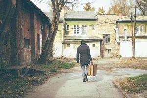 Rear view of a man walking with suitcase. photo