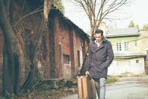 Pensive man walking while carrying a suitcase. photo