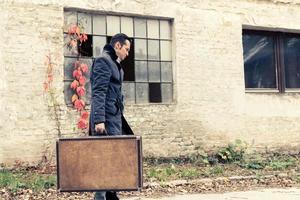 Side view of man with suitcase walking outdoors. photo