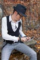 Stylish man with fedora hat using touchpad outdoors. photo