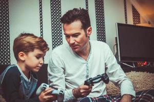 Small boy teaching his father how to use game controller. photo