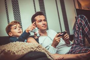 Father and son playing video games at home. photo