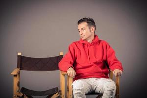 Sad man looking at empty chair beside him. photo