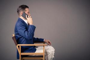 Side view of businessman talking on the phone against the wall. photo