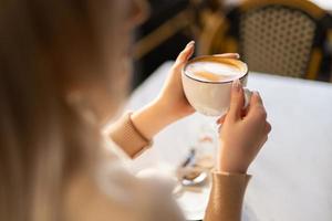 a fragrant and warm mug of cappuccino with a drawing heart,  girl  hold in hands. photo