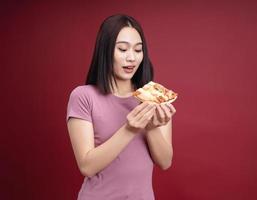 Young Asian woman eating pizza on background photo