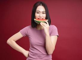 Young Asian woman eating watermelon on background photo