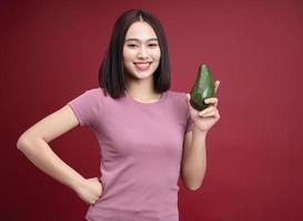 Young Asian woman holding avocado fruit on background photo