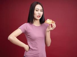 joven asiático mujer comiendo Pizza en antecedentes foto