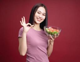 Young Asian woman eating salad on background photo
