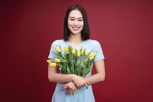 imagen de joven asiático mujer participación tulipanes flores en antecedentes foto