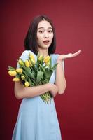 Image of young Asian woman holding tulips flowers on background photo