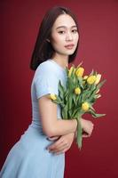 Image of young Asian woman holding tulips flowers on background photo