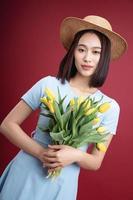 Image of young Asian woman holding tulips flowers on background photo