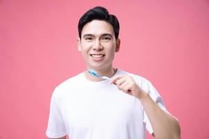 joven asiático hombre participación cepillo de dientes en antecedentes foto