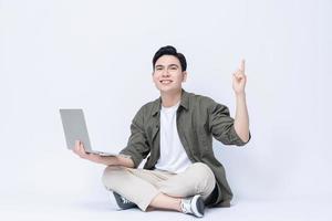 joven asiático negocio hombre sentado y utilizando ordenador portátil en antecedentes foto