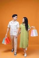 joven asiático Pareja participación compras bolso en antecedentes foto
