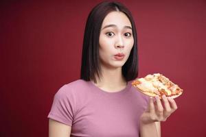 Young Asian woman eating pizza on background photo