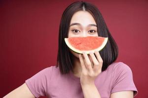 Young Asian woman eating watermelon on background photo