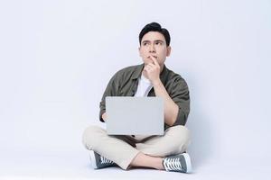 Young Asian business man sitting and using laptop on background photo