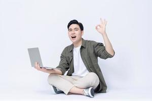 Young Asian business man sitting and using laptop on background photo