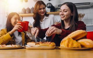 Young woman eating pizza and laughing while sitting with her friends in a restaurant. Group of friends enjoying while having food and drinks at cafe. photo