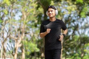 Man running wearing white headphone and smart watch while running or jogging at park. Sport healthy running concept. photo