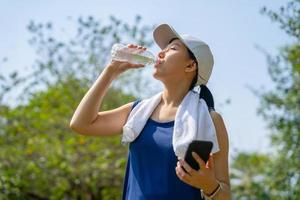 joven hermosa asiático Bebiendo agua después trotar corriendo exterior. deporte sano corriendo concepto. foto