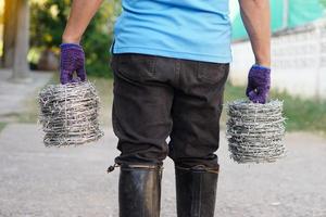 Closeup worker hand holds rolls of barbed wire. Concept, construction tool. Barbed wire is used for make fences , secure property ,make border to show the territory of  area. photo