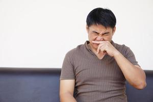 asiático hombre capturas un frío, que produce picor su nariz. concepto, salud problemas, alergia síntomas , estornudar ,tos, líquido nariz. foto